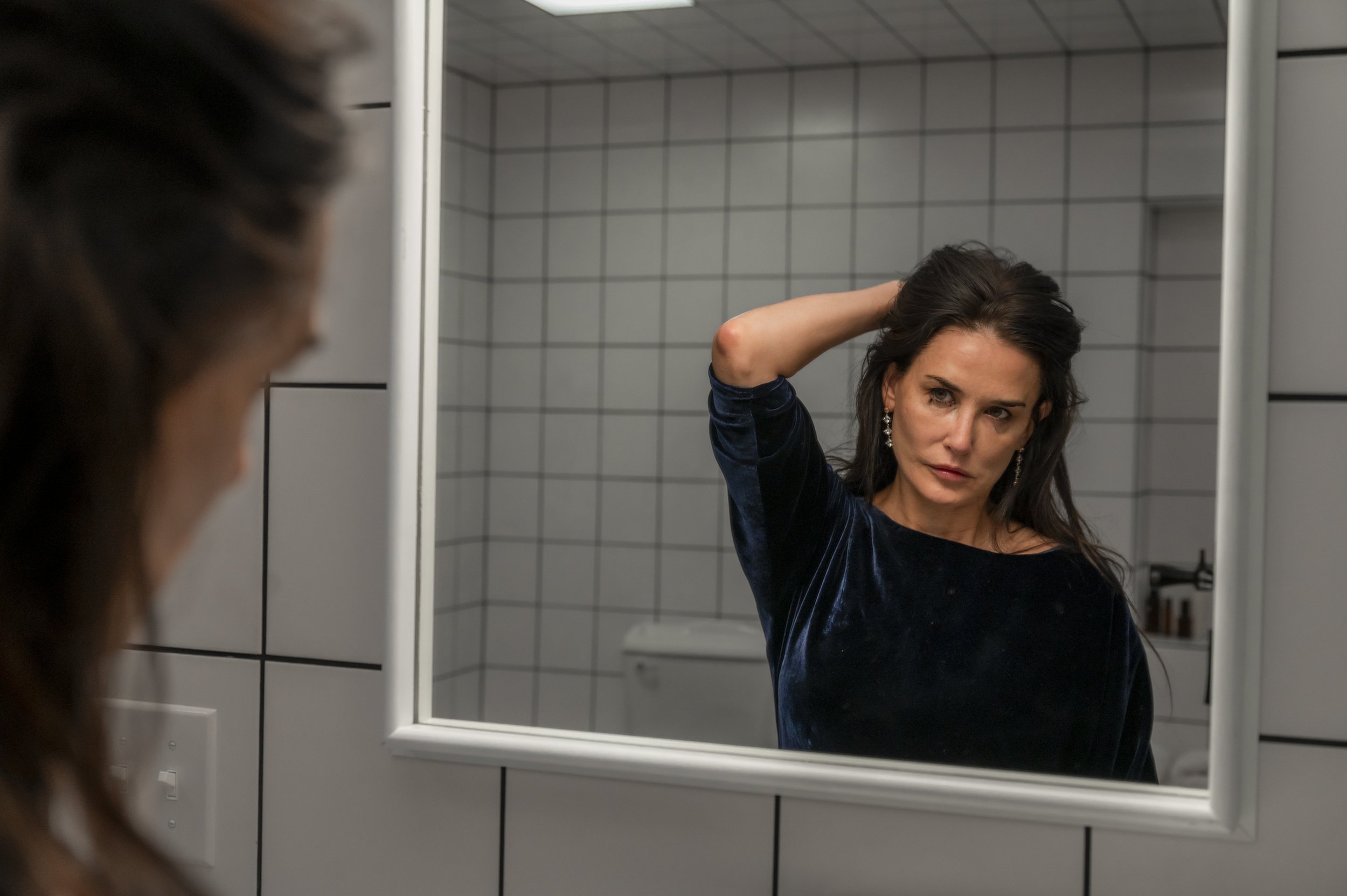 A still from The Substance of Demi Moore looking in the mirror.